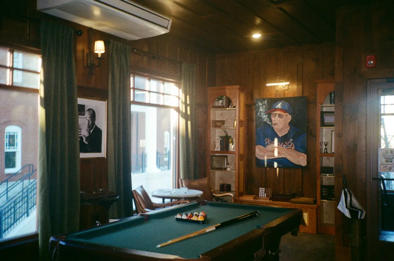 A wood-paneled club room with a full-size table and armchairs.